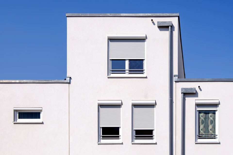 Façade moderne de bâtiment résidentiel avec volets roulants blancs partiellement fermés