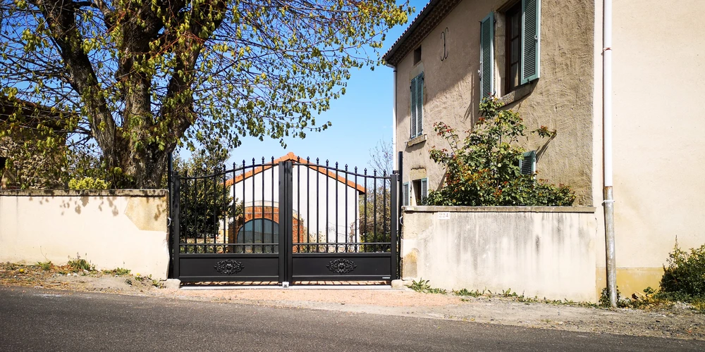 Portail battant double vantaux en aluminium noir, style classique avec décor en arabesque, barreaux verticaux et finials en pointe de lance