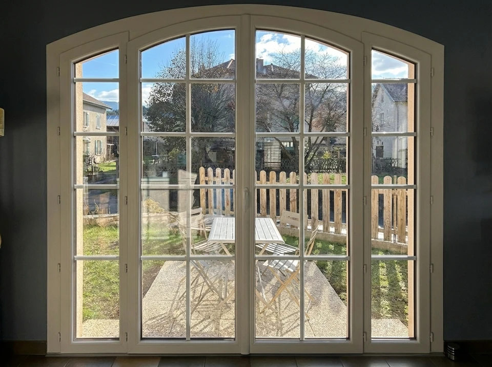 Balcon vitré fermé avec fenêtres PVC blanches ouvrantes donnant sur verdure urbaine